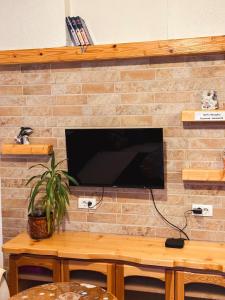 a flat screen tv on a brick wall with a table at Apartman Olivera in Žabljak
