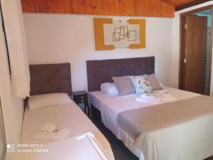 1 dormitorio con 2 camas y espejo en Pousada irmãos Oliveira en Lindóia