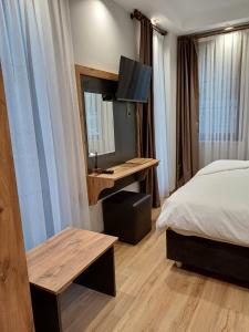 um quarto de hotel com uma cama, uma secretária e uma televisão em ÇARDAK ALTI OTEL em Trabzon