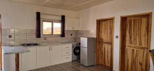 a kitchen with white cabinets and a washer and dryer at ROBINSON PLAGE Appartement in Lomé