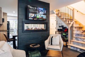 a living room with a tv on a black wall at Condo familale Spa et table Babyfoot, 350m de la montagne de ski in Mont-Blanc