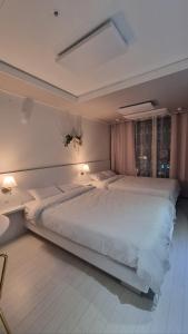 un grande letto bianco in una camera da letto con due lampade di Mia House a Daegu