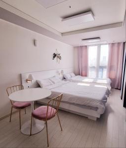 1 dormitorio con 1 cama, mesa y sillas en Mia House, en Daegu