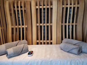 1 cama con 2 almohadas y control remoto en Tiny Villa de Haas met Infraroodsauna en Egmond aan Zee