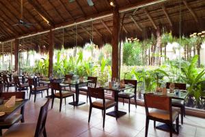 a dining room with tables and chairs and plants at El Dorado Seaside Suites Oceanfront, Catamarán, Ecoturistic Ranch, All & More Inclusive - Adults Only in Akumal