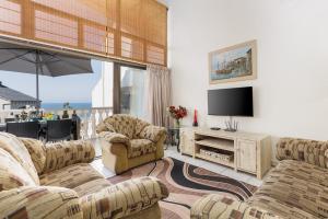 sala de estar con 2 sofás y TV de pantalla plana en Uvongo Cabanas 15B, en Margate