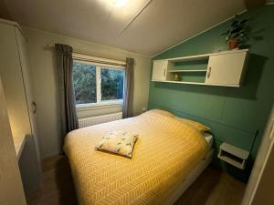 um pequeno quarto com uma cama e uma janela em Veluwe, gezellig 4p chalet bij bos, zonnige tuin em Otterlo
