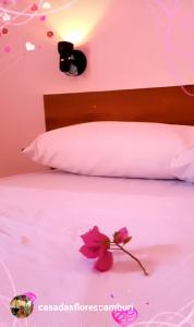 ein rosa Schlafzimmer mit einem Bett mit einer Blume darauf in der Unterkunft Pousada Casa das Flores Camburi in Camburi