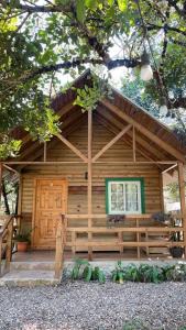 una cabaña de madera con un banco delante en Cabaña de campo en el lago de yojoa en Santa Cruz de Yojoa