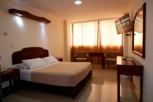 a hotel room with a bed and a table and chairs at Hotel Maria Gloria in Villavicencio