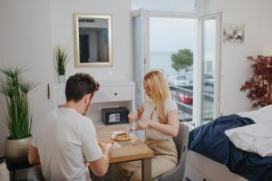 un homme et une femme assis à une table mangeant de la nourriture dans l'établissement Blue Pearl Elite Apartments, à Piran