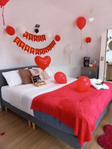 1 dormitorio con 1 cama con globos rojos y una señal en Sol y Luna Glamping, en Málaga