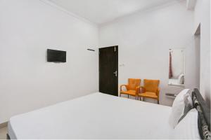um quarto branco com uma cama e 2 cadeiras laranja em Super OYO Hotel Goverdhan Villa em Udaipur