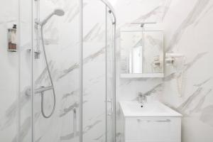 a white bathroom with a shower and a sink at GRAND CROWN in Vilnius