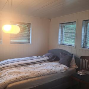 łóżko w pokoju z dwoma oknami w obiekcie GG overnatting w Stavangerze