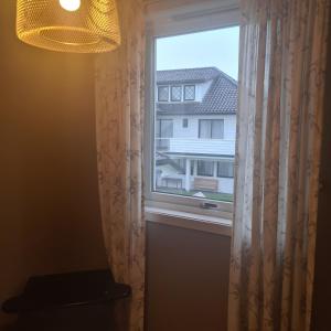 a window with a white curtain and a building at GG overnatting in Stavanger