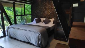 a bedroom with a bed and a large window at Wetlands Wayanad Resort with Natural Waterfalls in Padinjarathara