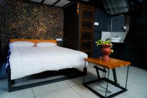 a bedroom with a bed and a table with a vase on it at Wetlands Wayanad Resort with Natural Waterfalls in Padinjarathara