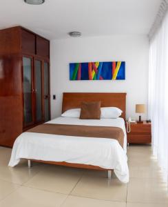 ein Schlafzimmer mit einem Bett und einem Wandgemälde in der Unterkunft Monterosa Apartamentos Amoblados in Pereira
