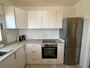 a kitchen with white cabinets and a stainless steel refrigerator at Terraza con vistas al mar Tenerife Norte Mesa del Mar in Tacoronte +27 photos