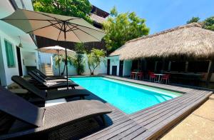a swimming pool with two chairs and an umbrella at Hotel Aqualuna Departamento #aussiepipe in Puerto Escondido