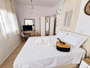 sypialnia z gitarą na białym łóżku w obiekcie Olympio Luxury Studio Paros w mieście Paros