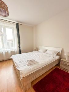 a bedroom with a large white bed with a red rug at Serenity House Apartments in Sibiu