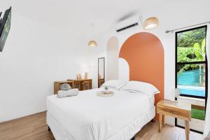 1 dormitorio con cama blanca y ventana en Casa Sunshine y Palmeras, en Matapalo