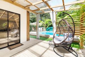 un patio con una silla mecedora junto a una piscina en Casa Sunshine y Palmeras en Matapalo