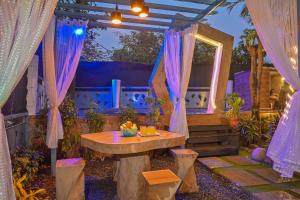 un patio con un tavolo e tende viola di Fortune Villa by Tropicana Stays a Lonavala