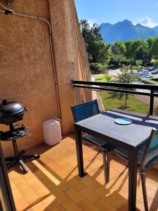 een tafel en stoelen op een balkon met een grill bij Studio bord de mer - Plage - Piscine - Wifi in Santa-Lucia-di-Moriani