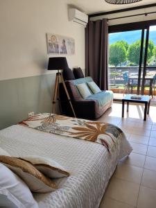 een slaapkamer met een bed, een bank en een raam bij Studio bord de mer - Plage - Piscine - Wifi in Santa-Lucia-di-Moriani