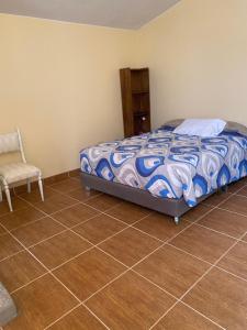 a bedroom with a bed and a chair and a tiled floor at Habitación cerca a los Pantanos de Villa in Lima