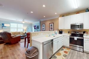 a kitchen with white cabinets and a living room at Friends Delight in Calabash