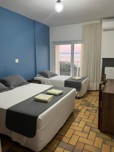 a bedroom with two beds and a large window at Hotel Quatro Estações in Guarapari