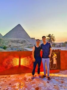 a man and a woman standing in front of the pyramids at Energy Of Pyramid Hotel in Cairo