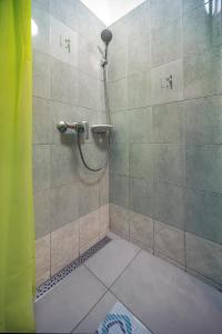 a shower with a hose in a tiled bathroom at Kordé Apartman in Kőszeg