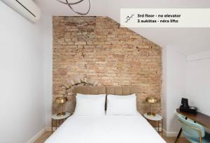 łóżko w pokoju z ceglaną ścianą w obiekcie GRAND CROWN w Wilnie