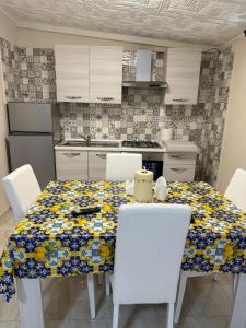 uma cozinha com uma mesa com cadeiras brancas e uma toalha de mesa em Casetta in villa indipendente em Angri