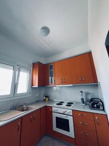 cocina con armarios rojos, fogones y fregadero en Ocean View Apartments, en Vrasná