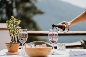 a person pouring wine into glasses on a table at Hotel Berghaus Rosengarten in Nova Levante