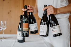 a man holding three bottles of wine on a table at Hotel Berghaus Rosengarten in Nova Levante