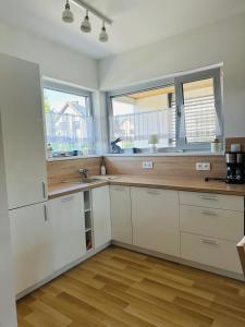 cocina con armarios blancos y 2 ventanas en Porto 13 - TRZĘSACZ SUNNY SIDE BALTIC, en Trzęsacz