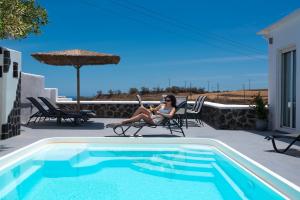 a woman sitting in a chair next to a swimming pool at Cave Sand in Monolithos