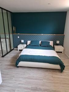 sypialnia z dużym łóżkiem i niebieską ścianą w obiekcie Chambre proche circuit 24h w mieście Le Mans