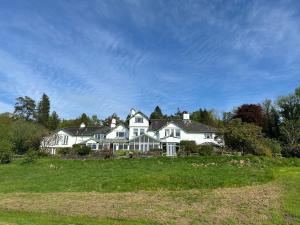 duży biały dom na zielonym polu w obiekcie The Ryebeck Hotel w mieście Bowness-on-Windermere