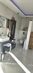 uma casa de banho branca com um lavatório e um WC em Chambres des délices em Villetelle