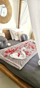 Dois cisnes estão sentados numa cama com rosas vermelhas. em Chambres des délices em Villetelle