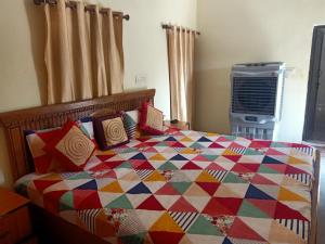 a bedroom with a colorful quilt on a bed at Khajuraho Rancho in Khajurāho