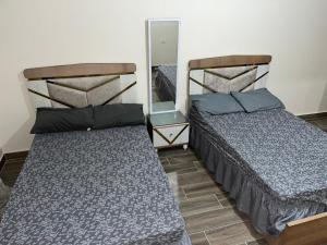 1 dormitorio con 2 camas y espejo en داون تاون العلمين الجديدة en ‘Ezbet `Abd el-Ḥamîd